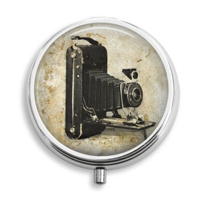 May include: A vintage black camera with a bellows and a lens on a textured background.