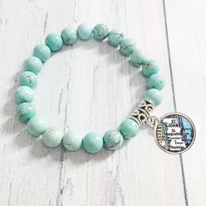 May include: A turquoise beaded bracelet with a silver charm featuring a map of St. Augustine, Florida.