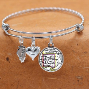 May include: A silver charm bracelet with three charms: a heart, a state of Illinois outline, and a map of DuPage County, Illinois.