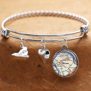 Puede incluir: Un brazalete de plata con tres dijes: un corazón, un mapa de McLean, Virginia, y el contorno del estado de Virginia.