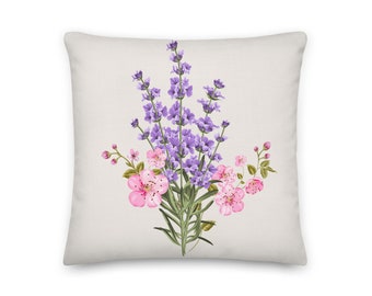Puede incluir: Una almohada decorativa con un diseño floral con flores rosas y moradas sobre un fondo blanco.