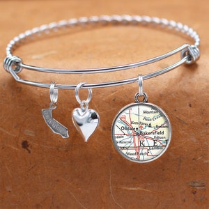 May include: A silver charm bracelet with three charms: a heart, a California outline, and a map of Bakersfield, California. The map charm features the text "Kern River", "Oildale", "Bakersfield", "Edison", "Lamont", and "Weed Patch".