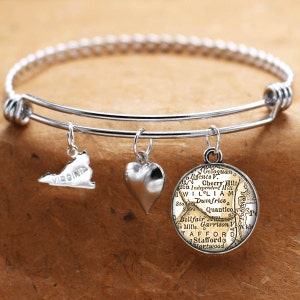 May include: A silver bangle bracelet with three charms: a heart, a silver outline of the state of Virginia, and a round charm with a vintage map of the Stafford, Virginia area.