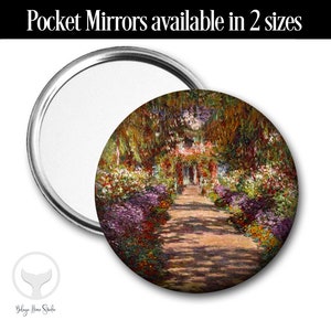 May include: A round pocket mirror with a colorful image of a garden path lined with flowers and trees. The image is reminiscent of a Monet painting.