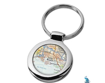 May include: A silver keyring with a round, map-like design featuring the text "Long Beach" and surrounding areas. The keyring has a silver ring for attaching to keys.