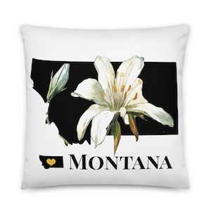 May include: White throw pillow with a black outline of the state of Montana and a white lily flower. The text "MONTANA" is printed below the state outline with a small yellow heart in the state outline.