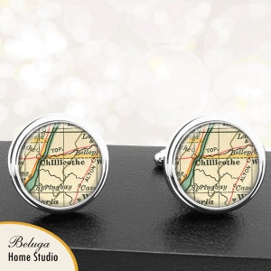 May include: A pair of silver cufflinks featuring a vintage map of Chillicothe, Ohio. The map is in shades of brown, green, and yellow, with the city name highlighted in red.