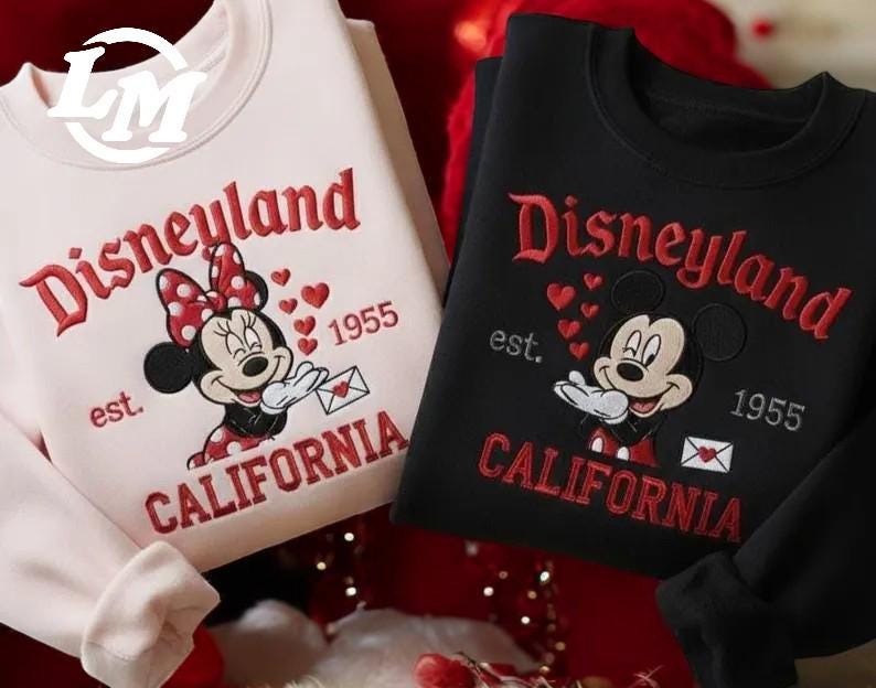 two sweatshirts with Disney characters and text, one in white and one in black, both with the text "Disneyland est. 1955" and "California" printed on them.
