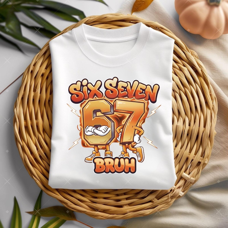 May include: White t-shirt with a graphic design featuring the words "Six Seven" above the number "67" and the word "BRUH" below. The numbers have arms and legs and are in orange and yellow colors.