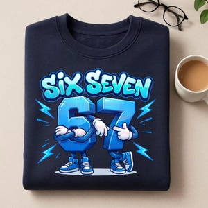 May include: Navy blue sweatshirt featuring the text "SIX SEVEN" in a blue, cartoon-style font. The numbers 6 and 7 are depicted as cartoon characters with arms, legs, and sneakers. Lightning bolt graphics are on either side.