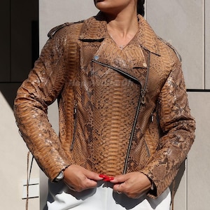 Può includere: Giacca marrone e beige con motivo a pelle di serpente e chiusura asimmetrica con zip. La giacca ha un colletto a revers, spalline e tasche con zip. Ha una vestibilità sartoriale ed è realizzata in un materiale strutturato.