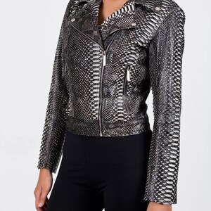 May include: A black and white snakeskin-patterned leather jacket with a zipper closure and a notched collar. The jacket has long sleeves and a fitted silhouette. The jacket is a stylish outerwear piece.