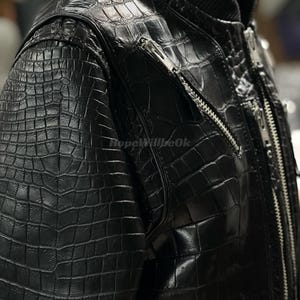 May include: Black leather jacket with a crocodile skin effect. The jacket features a ribbed collar and multiple silver zippers. The texture is detailed, suggesting a high-end garment.