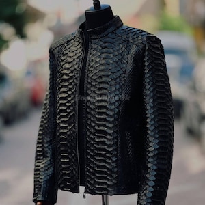 May include: A black leather jacket with a snakeskin pattern. The jacket has a stand-up collar, a zipper closure, and long sleeves. The jacket is displayed on a mannequin.