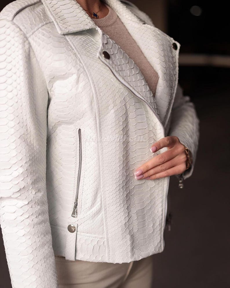 Puede incluir: Chaqueta de cuero blanca con estampado de piel de serpiente. La chaqueta tiene cuello con solapas, cierre de cremallera y un peque&ntilde;o bolsillo con cremallera en el pecho. La chaqueta tiene un corte entallado y es una opci&oacute;n de abrigo elegante.