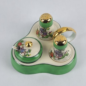 May include: A vintage ceramic salt and pepper set with a matching sugar bowl. The set features a green base and accents, with gold-colored lids and a handle. The pieces are decorated with a floral and pagoda design.