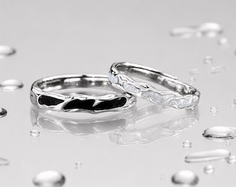 Puede incluir: Dos anillos de tono plateado con un diseño de banda irregular y orgánico. Un anillo presenta una incrustación negra lisa y brillante en el metal texturizado, mientras que el otro muestra una incrustación blanca brillante a lo largo.