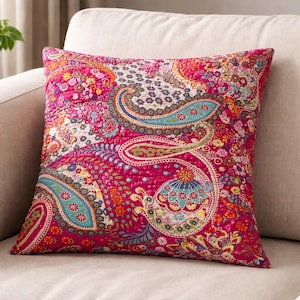 Könnte beinhalten: Ein quadratisches Zierkissen mit einem lebendigen Paisley-Muster. Das Kissen hat ein gestepptes Design mit einer reichen Farbpalette aus Fuchsia, Türkis, Orange und Gelb. Die Paisley-Motive sind aufwendig detailliert und schaffen einen optisch ansprechenden Stoff.