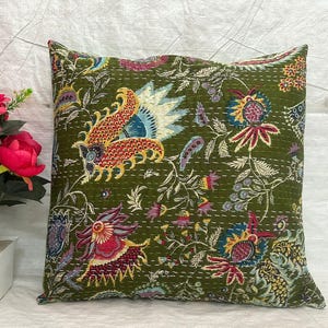 Könnte beinhalten: Quadratisches Zierkissen mit grünem Hintergrund und farbenfrohem Blumenmuster. Das Kissen hat ein detailliertes Design mit roten, blauen, gelben und weißen Akzenten. Es besteht wahrscheinlich aus Stoff und hat eine genähte Textur.