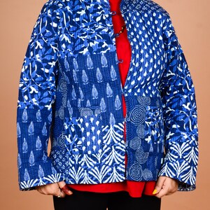 May include: A quilted jacket featuring a patchwork design of various blue and white patterns, including botanical motifs, circular swirls, and geometric shapes. The jacket has a mandarin collar, long sleeves, and a front closure with fabric toggles.