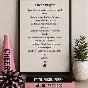 May include: A framed print titled Cheer Prayer with black text on a cream background, featuring a small illustration of a cheerleader. Below the frame are two stacked books with the text FAITH. FOCUS. FINISH. and ALL GLORY TO GOD.