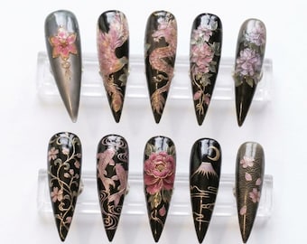 May include: A set of ten long, pointed artificial nails with intricate designs. The nails feature various Japanese-inspired art, including cherry blossoms, koi fish, and a dragon, in shades of pink, gold, and black.