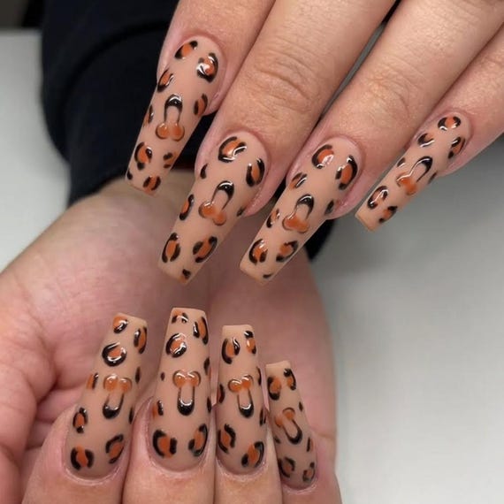Handmade 3D press-on nails combining leopard print with phallic nail art — unhinged, specific, and genuinely requiring skill to execute.
