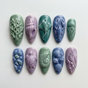 May include: A set of ten press-on nails featuring three-dimensional ocean-themed designs in shades of sage green, lavender, and periwinkle blue. The raised motifs include coral, seashells, a stingray, a lobster, a jellyfish, a turtle, and seaweed.