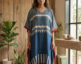 May include: A knee-length kaftan dress featuring a V-neckline and short sleeves. The garment displays a blue and cream colour palette with horizontal stripes, a geometric triangle pattern across the chest, and vertical stripes at the hem, finished with red trim.