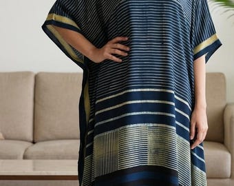 May include: A navy blue kaftan featuring a V-neckline and short, wide sleeves. The garment displays a pattern of horizontal white stripes and blocks of vertical lines, with a yellow-gold border along the edges and small tassels at the hem.