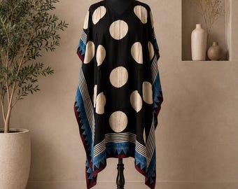 May include: A black kaftan featuring large cream-coloured polka dots, a V-neckline, and wide sleeves. The hem and sleeve edges are decorated with blue and white striped patterns, a dark red border, and small blue tassels at the bottom corners.
