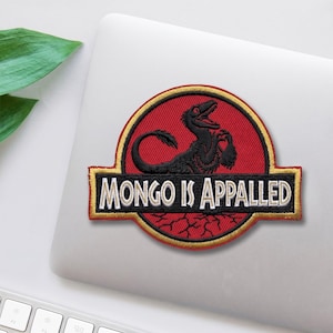 May include: Embroidered patch featuring a black dinosaur-like creature inside a red circle with a gold border. The patch has the text "MONGO IS APPALLED" in white letters on a black and gold rectangle.