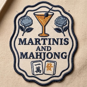 May include: Embroidered patch with a cream background and navy blue border. The patch features a martini glass, blue floral accents, and the words "MARTINIs AND MAHJONG." Two Mahjong tiles are at the bottom.