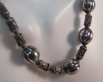 May include: A silver necklace featuring round, textured beads. The beads are linked together by a silver chain.