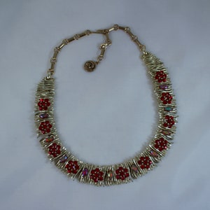 May include: A gold tone necklace with a chain and a red rhinestone design.