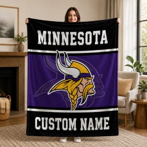 May include: A rectangular fleece blanket featuring a purple and black color scheme with the word MINNESOTA in white block letters at the top and CUSTOM NAME in white block letters at the bottom, centered with a Minnesota Vikings logo.