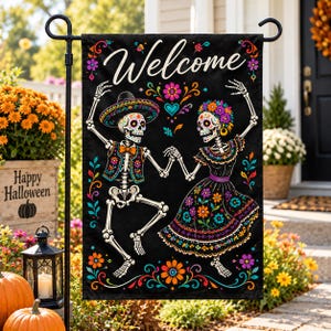 May include: A black garden flag featuring the white text Welcome at the top. The design displays two skeletons dancing, one wearing a sombrero and vest, the other in a floral dress. Both are surrounded by colorful flowers and decorative patterns.