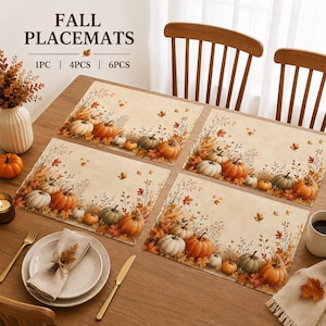 May include: Rectangular placemats featuring a printed autumn theme with orange and white pumpkins, brown and yellow fall leaves, and thin branches on a cream background. The text FALL PLACEMATS is printed at the top with 1PC, 4PCS, and 6PCS options.