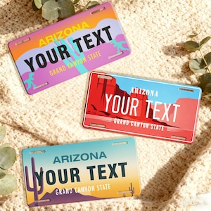 May include: Three Arizona license plates with the text "YOUR TEXT" in bold white letters. Each plate features a different desert landscape design with the words "ARIZONA" and "GRAND CANYON STATE". The plates are in shades of purple, red, and blue.