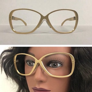 May include: Gold-toned oversized eyeglasses with a square frame and clear lenses.