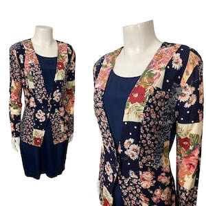 May include: A navy blue dress with a floral print jacket. The jacket has a patchwork design with different floral patterns in shades of pink, red, and white.