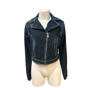 May include: A dark wash denim jacket with a zip-up front and two zippered pockets. The jacket has a classic collar and long sleeves. The jacket is displayed on a mannequin.