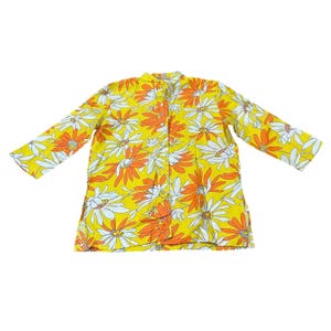 May include: A long-sleeved, button-down shirt with a vibrant floral pattern. The shirt features a yellow background with large orange and white daisy-like flowers. The shirt is made of a lightweight material.