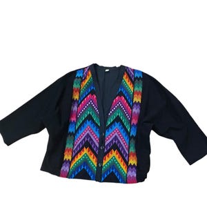May include: Black cardigan with a vibrant, multicolored chevron pattern on the front. The pattern incorporates shades of red, orange, yellow, green, blue, and purple. The cardigan has a V-neck and button closure.