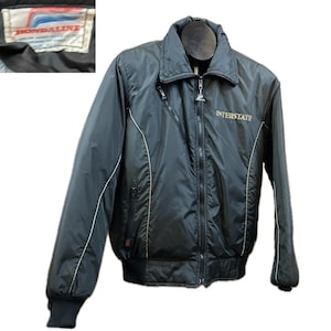 May include: Black motorcycle jacket with a zip-up front, a stand-up collar, and white trim. The jacket has the word "INTERSTATE" in gold lettering on the chest. The jacket also has a "HONDALINE" label.