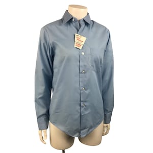 May include: A light blue long-sleeved button-down shirt with a single pocket on the left chest. The shirt has a tag that reads "Soft Release Tapered Stays".