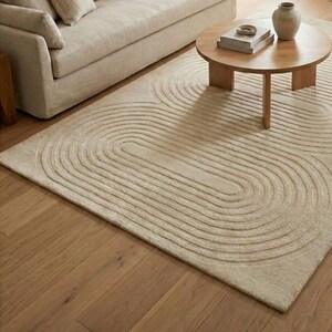 Handmade tufted area rug 8x10 featuring modern organic curves in a light neutral palette. The dense wool surface feels luxurious and inviting, perfect for family gatherings or quiet evenings. Complements wood floors, simple sofas, and natural decor elements. A stylish solution for large living rooms or bedrooms seeking warmth and harmony.