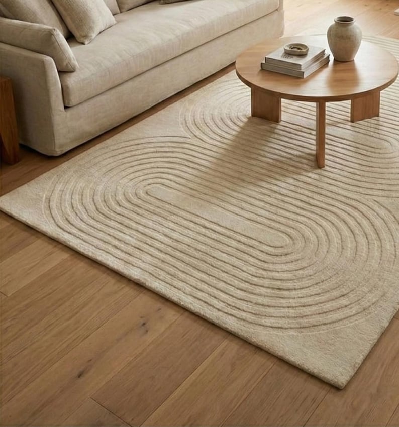 Handmade tufted area rug 8x10 featuring modern organic curves in a light neutral palette. The dense wool surface feels luxurious and inviting, perfect for family gatherings or quiet evenings. Complements wood floors, simple sofas, and natural decor elements. A stylish solution for large living rooms or bedrooms seeking warmth and harmony.