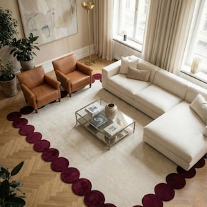 Elegant scalloped hand tufted rug 8x10 in ivory and burgundy placed over herringbone wood floor. The circular border creates a playful yet sophisticated frame, making the room feel curated, balanced and inviting. Great for contemporary homes and designer spaces.