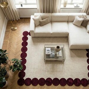 Contemporary burgundy scallop edge rug 5x8 crafted by artisans using hand tufting techniques. The elegant round shapes wrap around the neutral middle, creating depth and movement. Perfect for apartments, bedrooms or chic sitting areas where a bold but refined carpet is desired.